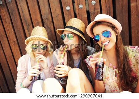 A picture of a group of girl friends drinking soda on the pier