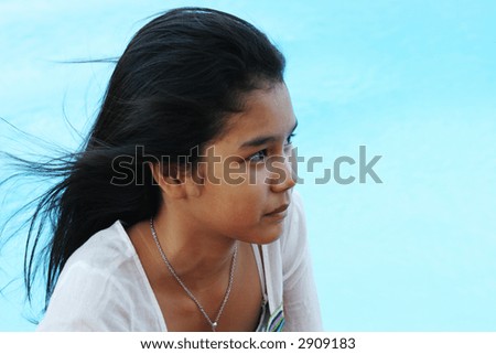 Happy girl with flowing hair relaxing by the swimming pool