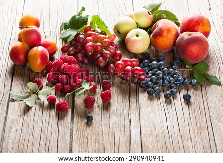 Organic fruits and berries with green leaves  on a rustic wooden background Royalty-Free Stock Photo #290940941