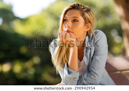 thoughtful woman sitting alone outdoors Royalty-Free Stock Photo #290942954