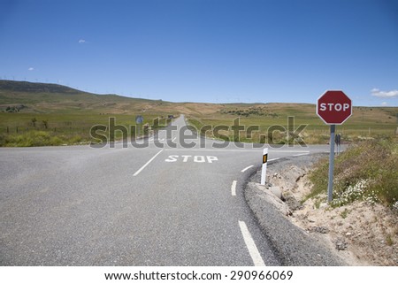 crossroad with stop symbol painted on asphalt and red hexagonal signal metal pole in rural road next to Madrid Spain Europe