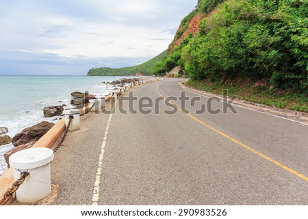 nice view of the road curve and pole beside sea beach and mountain 