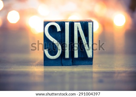 The word SIN written in vintage metal letterpress type on a soft backlit background.