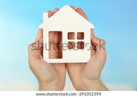 Female hands holding house on turquoise background