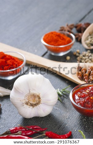 fresh and dried chili fruits, peppercorn, pepper powder, sauce and garlic, on old black wooden table background