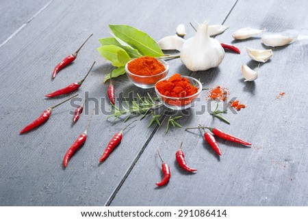 chili peppers, garlics, rosemary and bay leaves on black wooden surface