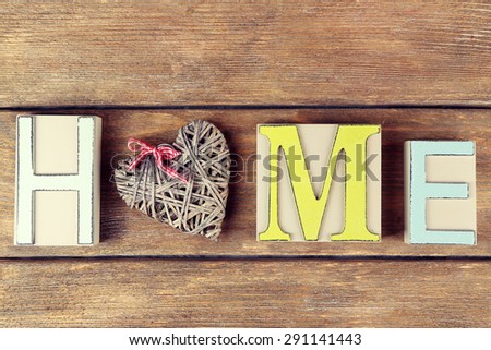 Decorative letters forming word HOME with decorative heart on wooden background