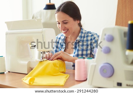 young woman working on sewing machine and smiling