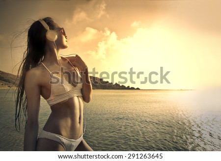 Young woman listening to music at the beach