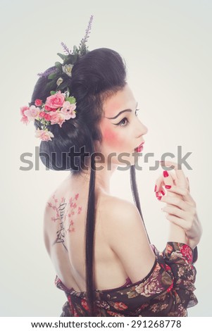 Attractive girl geisha. Drawing cherry and hieroglyphs on the back. The concept of Asian beauty.