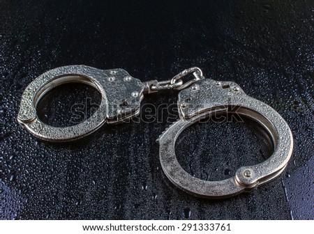 police handcuffs on a dark background in the drops of rain