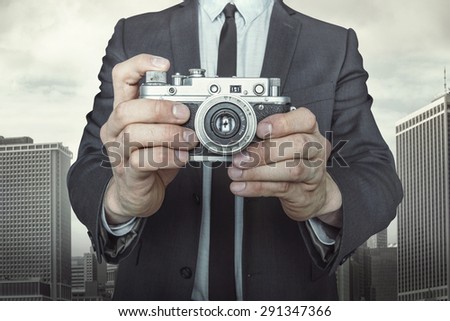 Businessman taking a photo with vintage camera on cityscape background