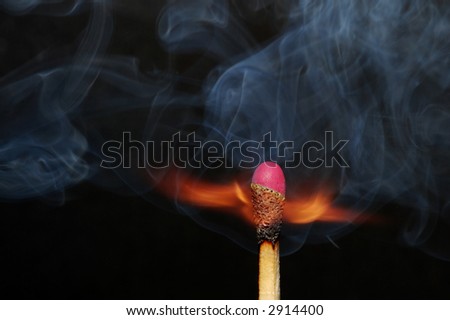 Photo of a burning match with smoke on a black background