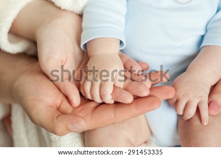 Mom and Dad hold baby's hand Royalty-Free Stock Photo #291453335