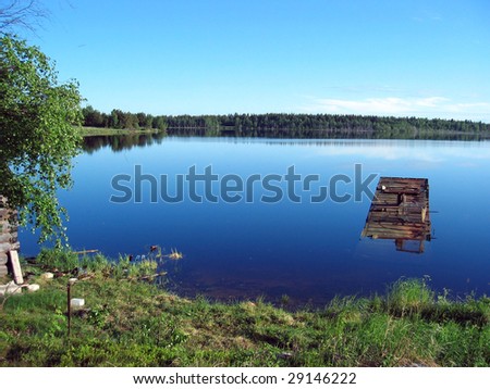 This is the picture of the quiet Karelian lake, cloudless sky and the distant forest