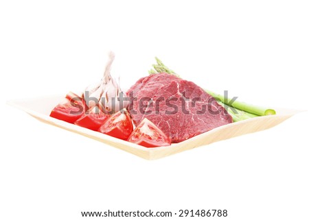 fresh raw beef meat steak fillet on wooden plate with asparagus and tomatoes ready to prepare isolated over white background