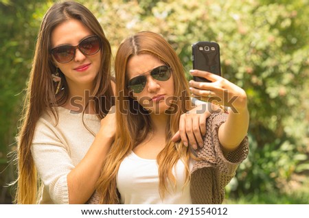 Girl friends wearing casual summer clothes posing for selfie with sunglasses