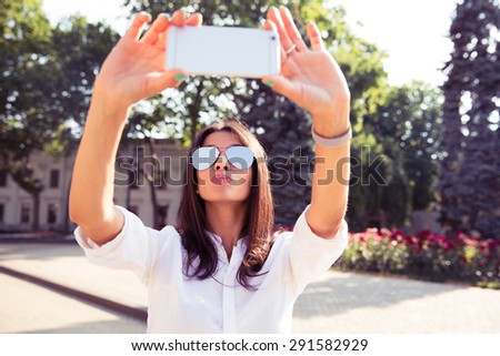 Glamorous girl making a selfie with her smartphone outdoors