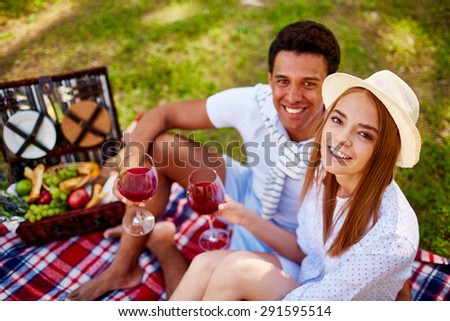 Happy dates with red wine looking at camera at picnic