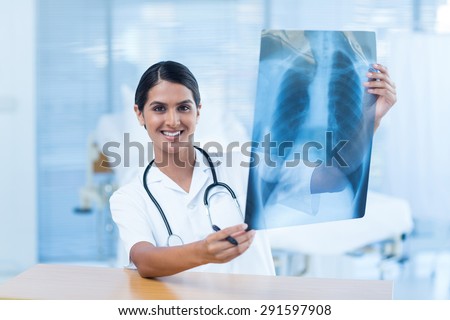 Beautiful smiling doctor analyzing xray in hospital room