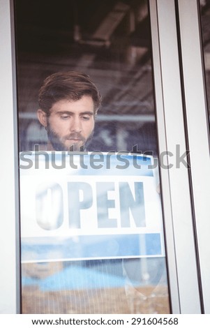 Smiling worker putting up open sign at the bakery