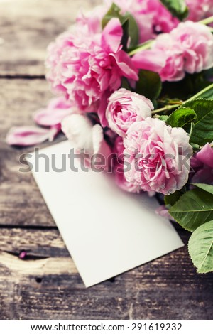 Beautiful peonies and roses with card on wooden background/ holidays romantic background