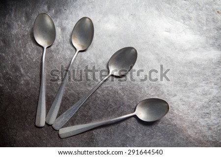 Empty old silver spoons on steel background