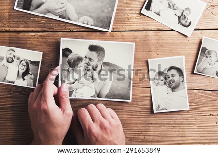 Black and white family photos laid on wooden floor background. Royalty-Free Stock Photo #291653849