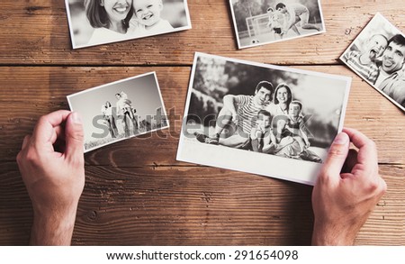 Black and white family photos laid on wooden table background.
