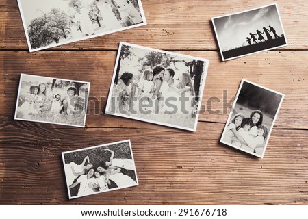 Black and white family photos laid on wooden floor background.
