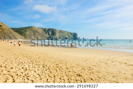 Beach in the Algarve region of Portugal. People swimming and surfing. 