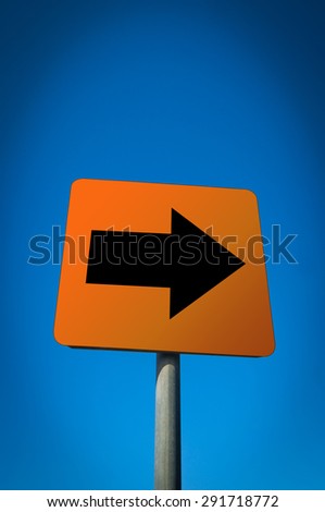 A black arrow red sign pointing to the right against blue sky