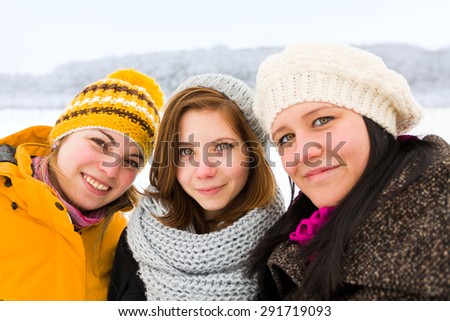 Smiling young girls taking a selfie outdoors in winter.