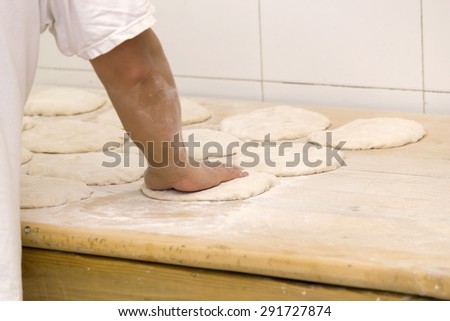 Hand of a baker preparing dough for bread in the bakery. Stock photography.