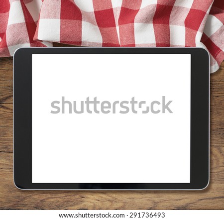 black tablet pc on wooden table and picnic tablecloth
