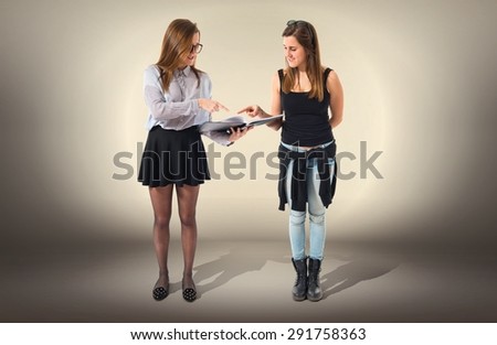 Twin sisters showing a book over textured background