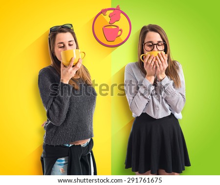 Twin sisters holding a cup of coffee over colorful background