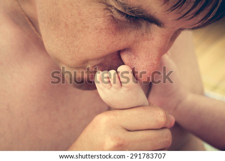 Father kisses foot of baby. Toned image. 