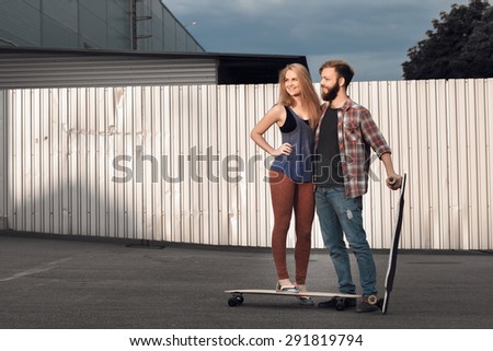 Young couple are holding skateboard outside