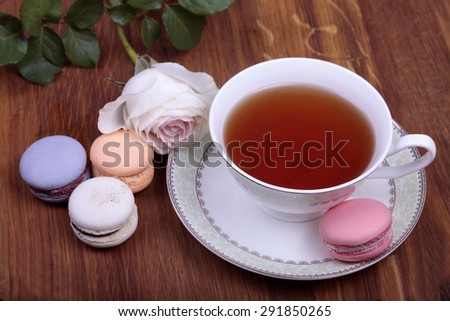 Cup of tea with colorful french macaron on wood background, selective focus