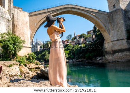 Female tourist photographing with professional photo camera old bridge in Mostar city in Bosnia and Herzegovina. 