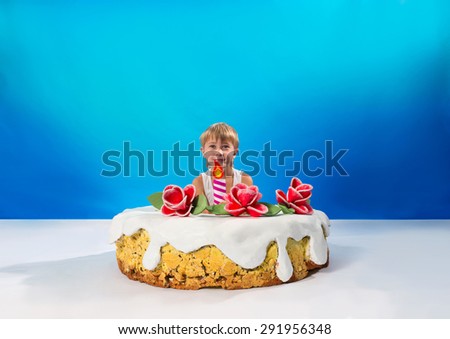 Cheerful boy sitting in the cake