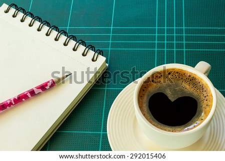 coffee cup with paper and pencil on green background