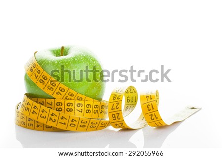 Dieting concept. Green apple with measuring tape on white background