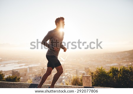 Young man training in the nature with sun behind him. Young man on morning run outdoors. Royalty-Free Stock Photo #292077806