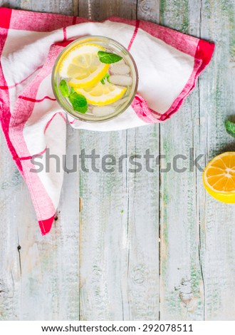 lemonade with ice, lemon slices and fresh mint in a glass, blue wood background, top view