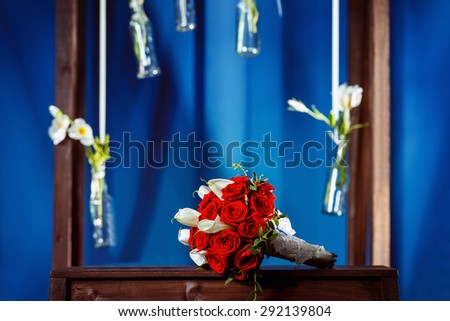 Closeup image of red roses wedding flowers  bouquet at blue interior studio background.