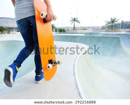 woman skateboarder hold skateboard walking at skatepark