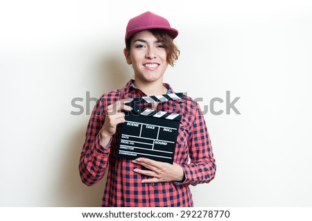 Girl in red shirt and cap smiling and showing movie clapper on white background