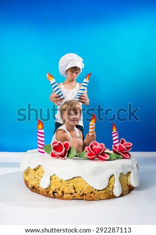 Two boys with big cake with colored candles